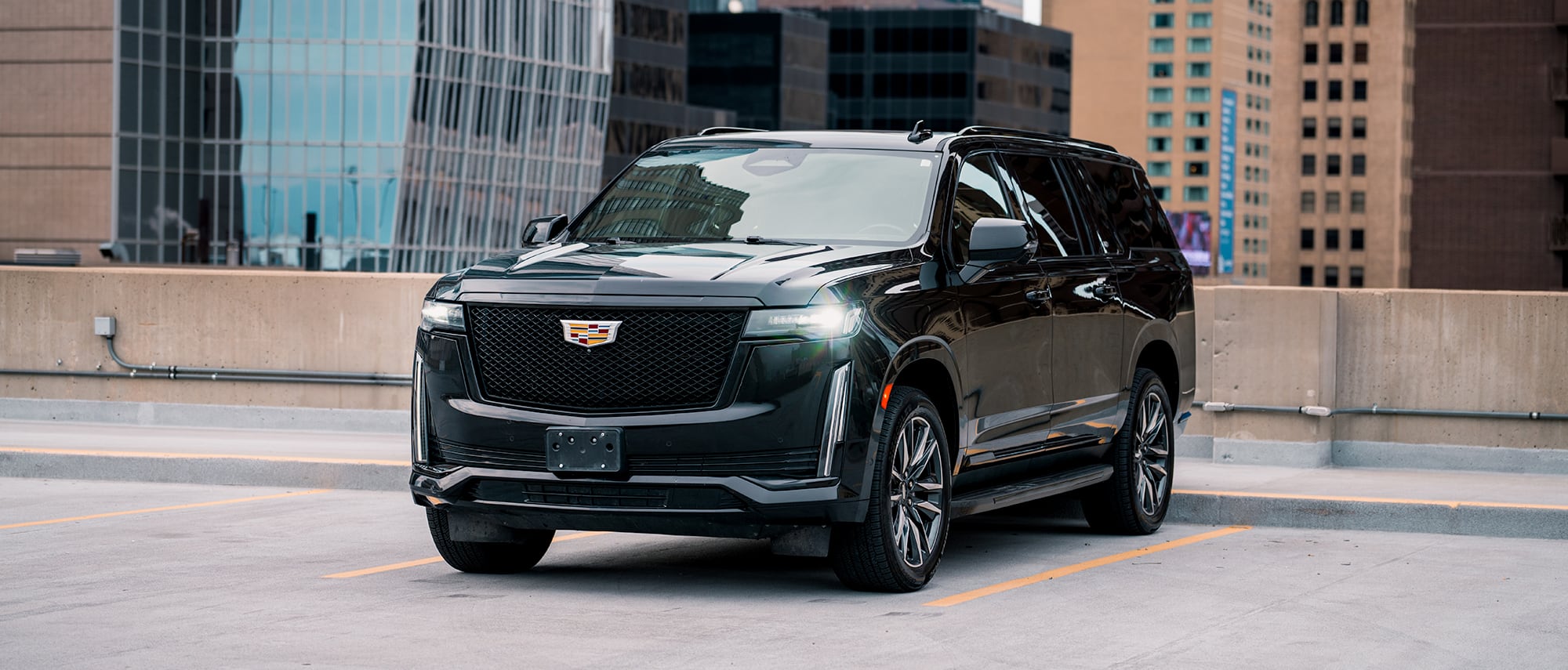 The lit headlamp and grille of a black VantaBLACK Escalade